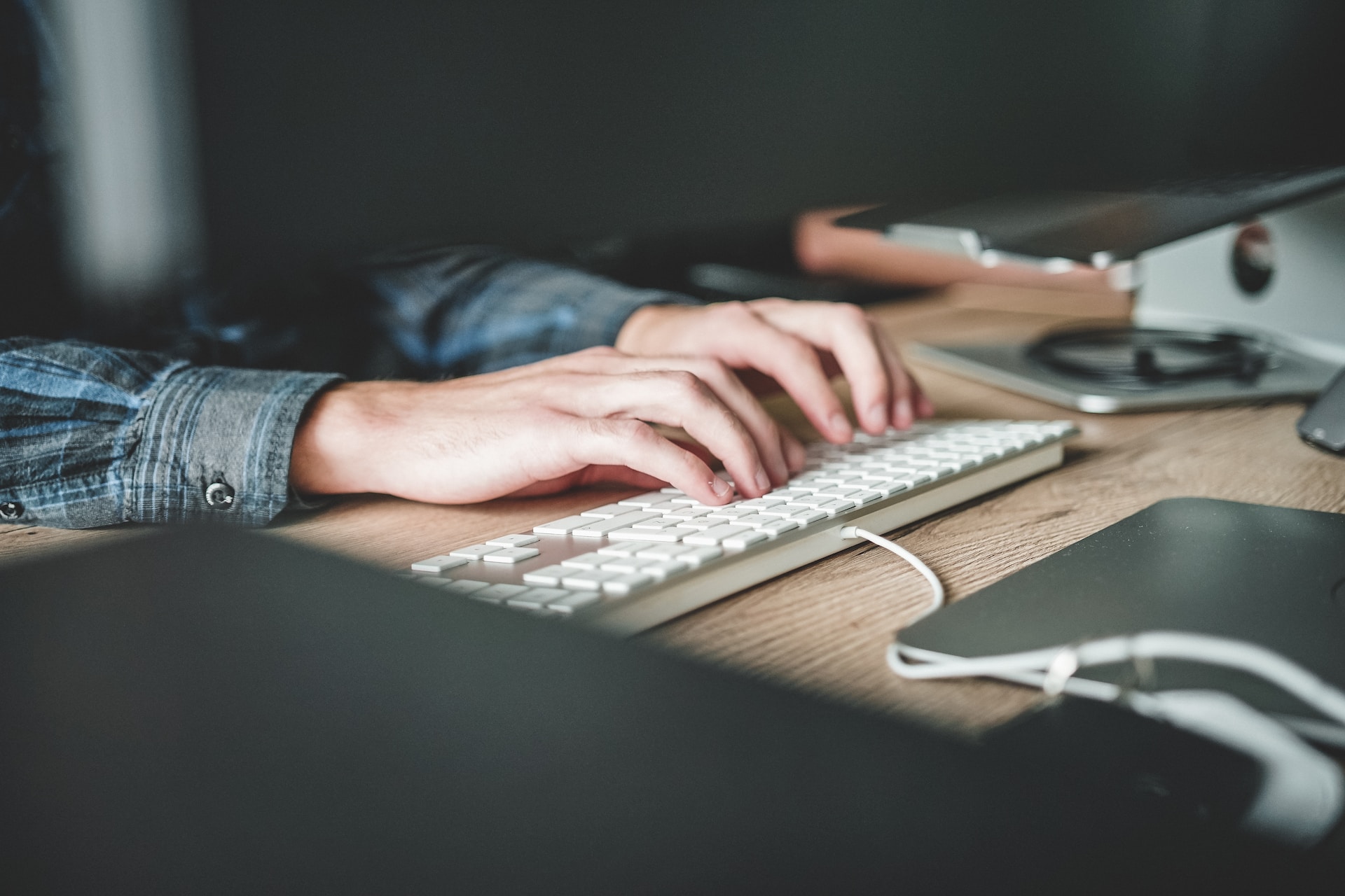 Two hands typing on a white keyboard