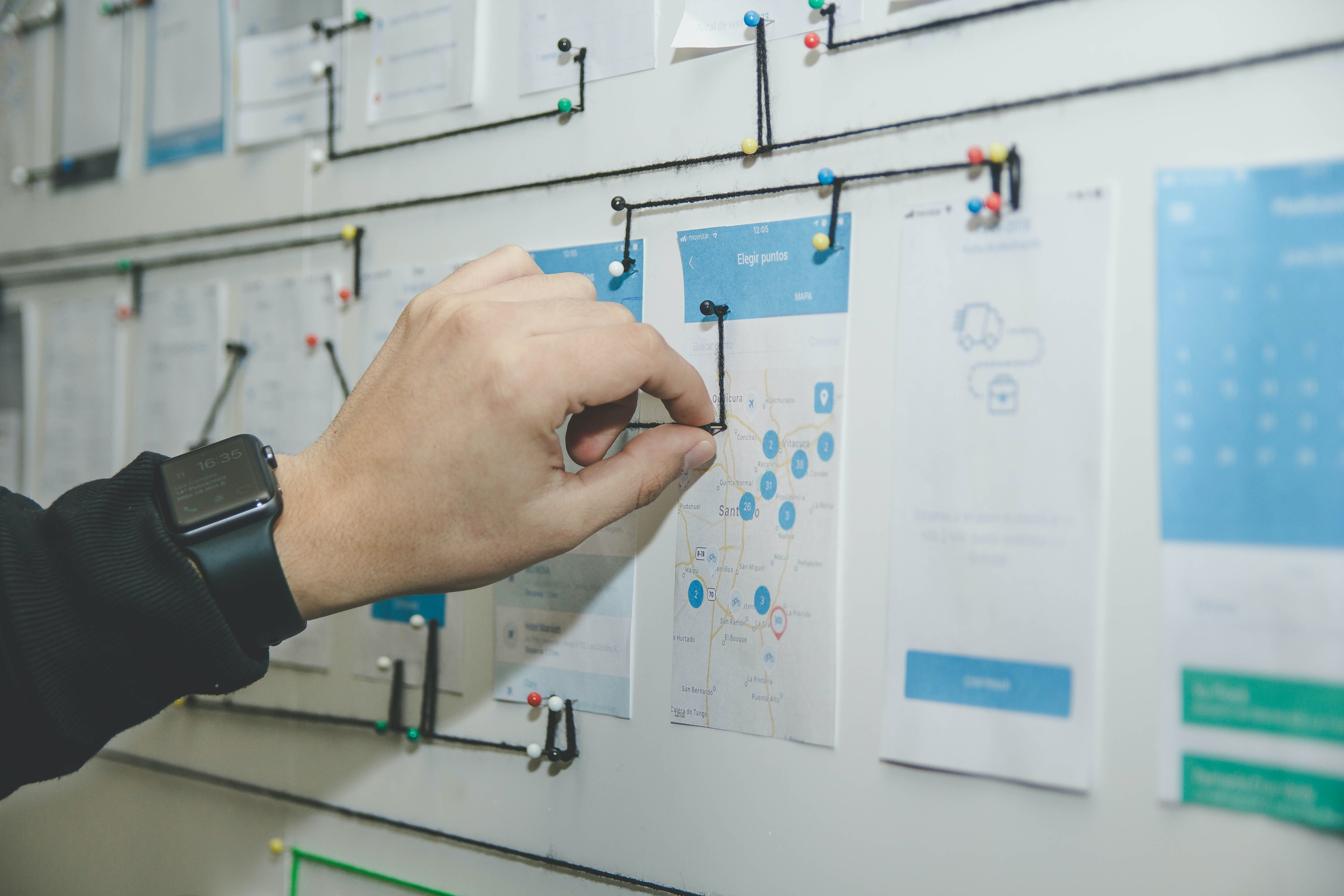 A male hand arranging UI wireframes on a board