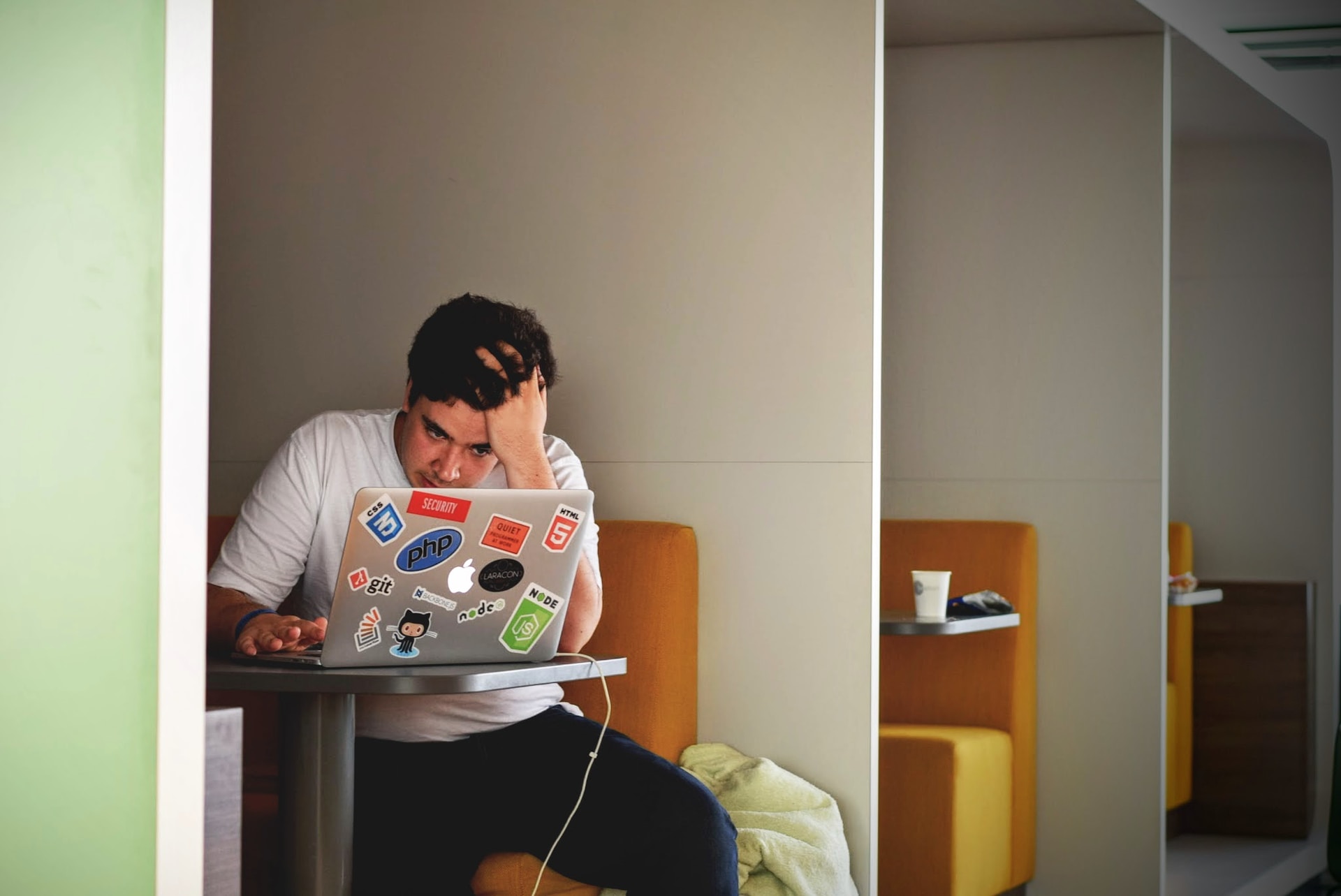 A man pulling his hair staring at a laptop which has been decorated with colourful stickers