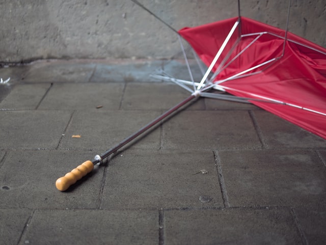 A broken red umbrella on the pavement