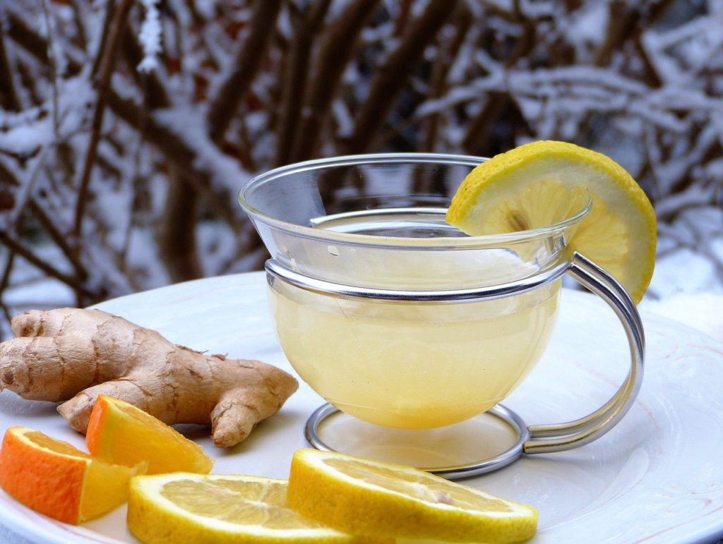 Lemon ginger tea with some lemon wedges and ginger root on the side